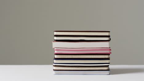 Close-up-of-stack-of-books-on-grey-background,-in-slow-motion