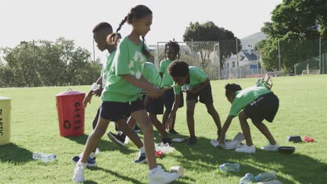 Escolares-Felices-Y-Diversos-Con-Camisetas-Recicladas-Limpiando-El-Campo-Deportivo-En-La-Escuela-Primaria
