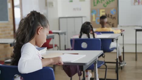 Focused-diverse-schoolchildren-writing-at-desks-in-elementary-school-classroom,-slow-motion