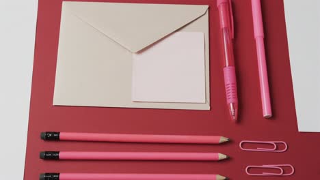 Nahaufnahme-Von-Stiften,-Bleistiften-Und-Schreibwaren-Auf-Rotem-Hintergrund,-In-Zeitlupe