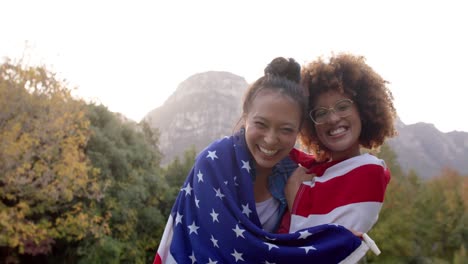 Portrait-of-happy-diverse-female-friends-holding-flag-of-usa-and-celebarting-in-garden,-slow-motion