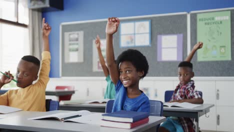 Happy-diverse-schoolchildren-at-desks-raising-hands-in-elementary-school-classroom-in-slow-motion
