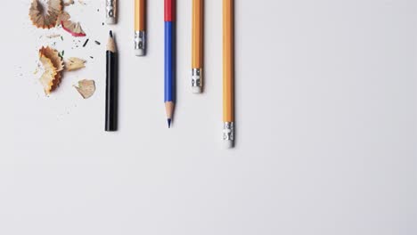 Overhead-view-of-pencils-and-pencil-sharpener-on-white-background,-in-slow-motion