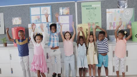Portrait-of-happy-diverse-schoolchildren-raising-hands-over-ecology-texts-at-elementary-school