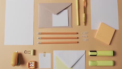 Overhead-view-of-pens,-pencils-and-stationery-arranged-on-beige-background,-in-slow-motion