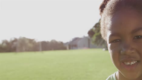 Portrait-of-happy-african-american-schoolgirl-smiling-in-sports-field-at-elementary-school