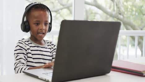 Fröhliches-Afroamerikanisches-Mädchen-Mit-Laptop-Und-Kopfhörern-Im-Online-Unterricht,-Zeitlupe