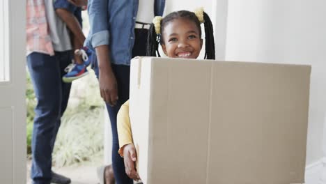 Glückliches-Afroamerikanisches-Paar-Mit-Sohn-Und-Tochter,-Die-Kisten-Ins-Haus-Bringen,-Zeitlupe