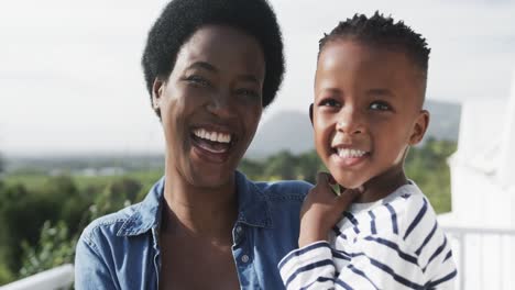 Glückliche-Afroamerikanische-Mutter-Und-Sohn-Auf-Sonniger-Terrasse,-Zeitlupe