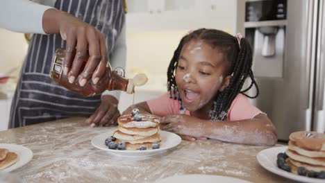 Glückliche-Afroamerikanische-Mutter-Und-Tochter-Servieren-Pfannkuchen-In-Der-Küche,-Zeitlupe