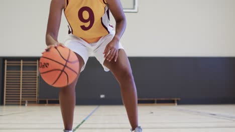 Portrait-of-african-american-female-basketball-player-training-in-indoor-court,-in-slow-motion