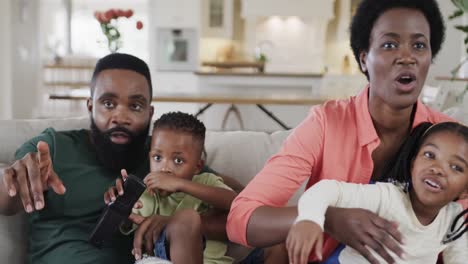 Excited-african-american-parents-with-son-and-daughter-watching-sport-on-tv-at-home,-slow-motion