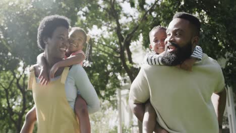 Glückliches-Afroamerikanisches-Paar-Mit-Sohn-Und-Tochter,-Die-Im-Sonnigen-Garten-Spazieren-Gehen,-Zeitlupe