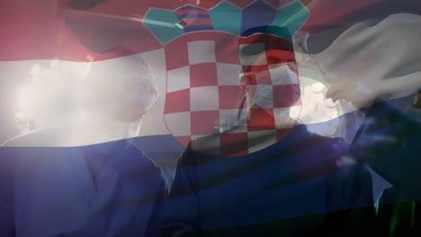 Animation-of-waving-croatia-flag-over-team-of-diverse-surgeons-performing-surgery-at-hospital