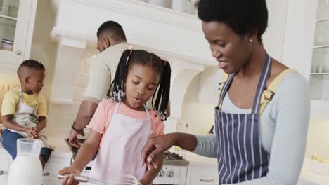 Happy-african-american-couple-with-son-and-daughter-in-aprons-preparing-meal-in-kitchen,-slow-motion