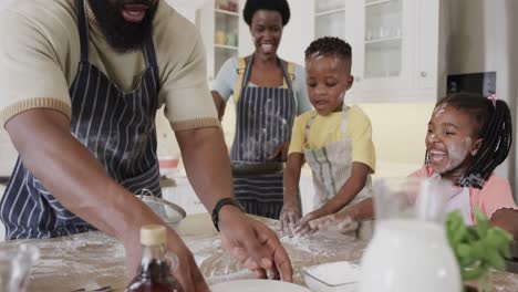 Happy-african-american-couple-with-son-and-daughter-in-aprons-preparing-meal-in-kitchen,-slow-motion