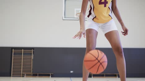 Portrait-of-african-american-female-basketball-player-training-in-indoor-court,-in-slow-motion