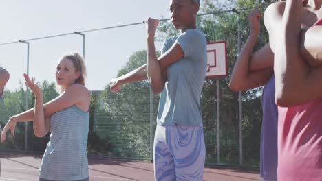 Happy-diverse-female-basketball-team-training-on-sunny-court,-in-slow-motion