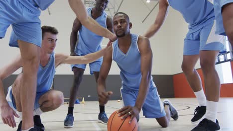 Diverse-male-basketball-team-training,-congratulating-player-doing-press-ups-on-ball,-slow-motion
