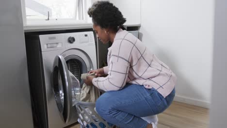 Afroamerikanische-Frau-Legt-Kleidung-In-Die-Waschmaschine,-Wäscht-Zu-Hause-Wäsche,-Zeitlupe
