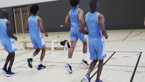 Diverse-male-basketball-team-training,-running-and-turning-on-indoor-court,-slow-motion