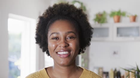 Retrato-De-Una-Feliz-Mujer-Afroamericana-Sonriendo-En-Una-Cocina-Soleada,-En-Cámara-Lenta