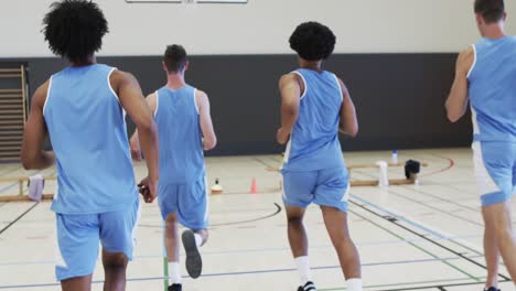 Diverse-male-basketball-team-training,-running-and-turning-on-indoor-court,-slow-motion