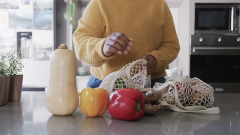 Midsection-of-african-american-woman-unpacking-groceries-in-kitchen,-in-slow-motion