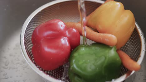 Close-up-of-vegetables-in-colander-rinsing-in-kitchen-sink,-slow-motion