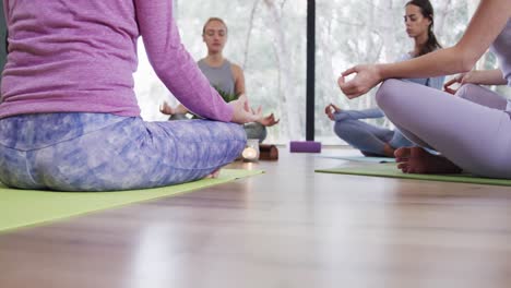 Diversas-Mujeres-Meditando-En-Pose-De-Loto-Mientras-Se-Sientan-En-Esteras-En-Un-Estudio-De-Yoga