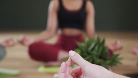 Diverse-women-practicing-patience-mudra-while-meditating-together-in-yoga-studio