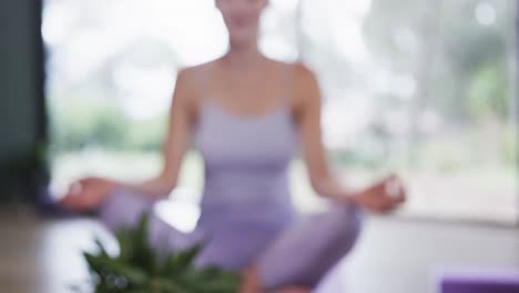 Diverse-women-practicing-patience-mudra-while-meditating-in-yoga-studio