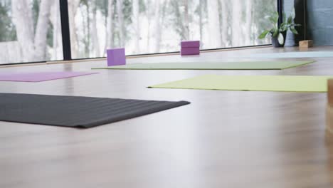 Colorful-yoga-mats-with-cork-blocks-and-singing-bowl-on-floor-in-yoga-studio