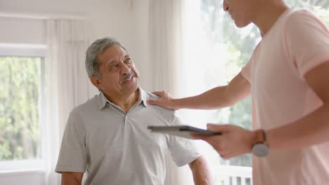 Diverse-male-physiotherapist-with-tablet-shaking-hands-with-senior-male-patient,-in-slow-motion