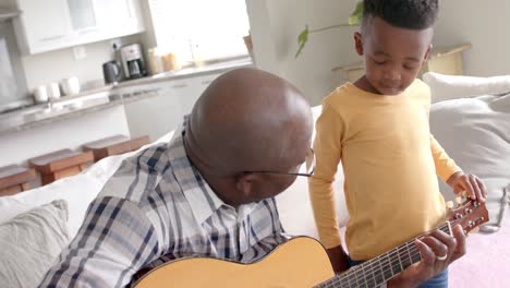 Glücklicher-Afroamerikanischer-Großvater-Und-Enkel,-Die-Zu-Hause-Gemeinsam-Gitarre-Spielen,-Zeitlupe