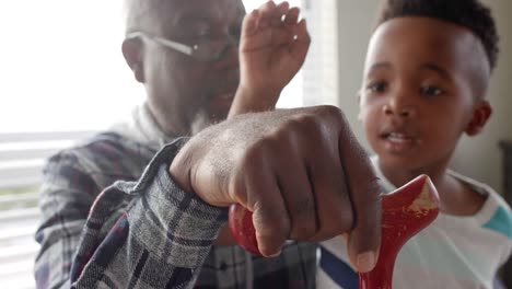 Close-up-of-african-american-grandfather-and-grandson-stacking-hands-at-home,-slow-motion