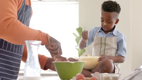 Glücklicher-Afroamerikanischer-Großvater-Und-Enkel-Lächeln,-Backen-In-Der-Küche,-Zeitlupe