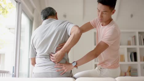 Diverse-male-physiotherapist-examining-senior-male-patient,-in-slow-motion