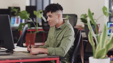Happy-biracial-male-creative-using-tablet-and-computer-at-casual-office,-in-slow-motion