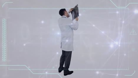 Animation-of-glowing-network-of-connections-over-caucasian-male-doctor-examining-x-ray-report
