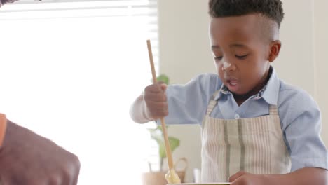 Happy-african-american-grandfather-and-grandson-smiling,-baking-in-kitchen,-slow-motion