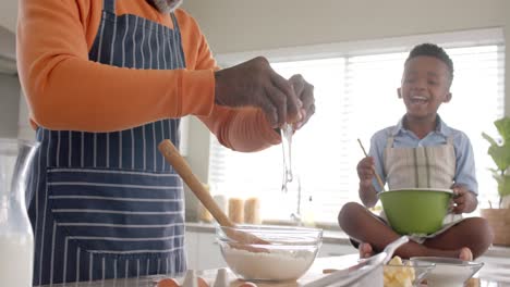 Feliz-Abuelo-Y-Nieto-Afroamericano-Horneando-En-La-Cocina,-Cámara-Lenta