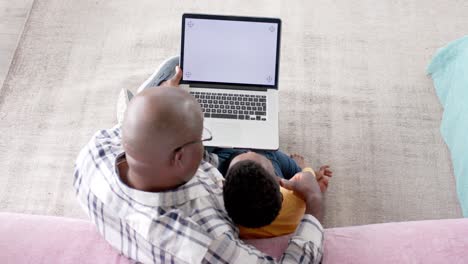 African-american-grandfather-using-tablet-with-grandson-at-home,-slow-motion,-copy-space-on-screen