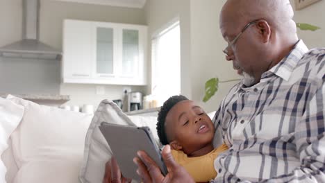 Abuelo-Afroamericano-Con-Nieto-Usando-Tableta-En-El-Sofá-En-Casa,-Cámara-Lenta