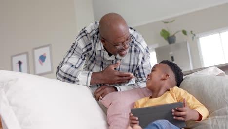 African-american-grandfather-with-grandson-using-tablet-at-home,-slow-motion