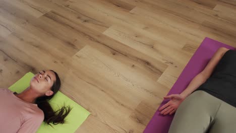 Focused-diverse-women-lying-together-on-mats-in-yoga-class-with-female-coach,-slow-motion