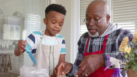 African-american-grandfather-and-grandson-high-fiving,-planting-flowers-on-balcony,-slow-motion