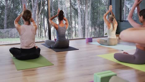 Focused-diverse-women-meditating-together-on-mats-in-yoga-class-with-female-coach,-slow-motion