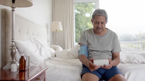 Biracial-älterer-Mann-Testet-Zu-Hause-Im-Bett-Den-Blutdruck,-Zeitlupe