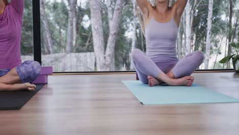 Focused-diverse-women-meditating-together-on-mats-in-yoga-class,-slow-motion